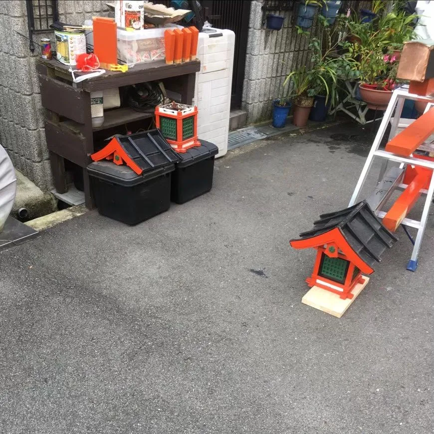 屋外に並べた赤い木製部材、脚立、道具類