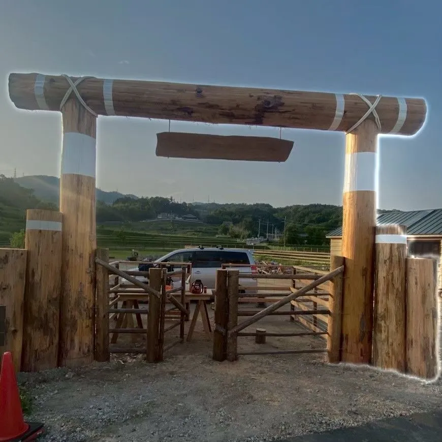 屋外に立つ、丸太を組んだ木製ゲートの正面寄りの全景