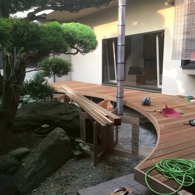 住宅の庭に設けた、縁が曲線を描く木製のウッドデッキ