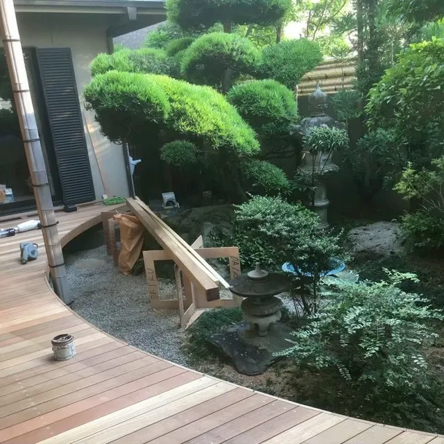 庭の植栽に沿って曲線状に延びるウッドデッキの全景