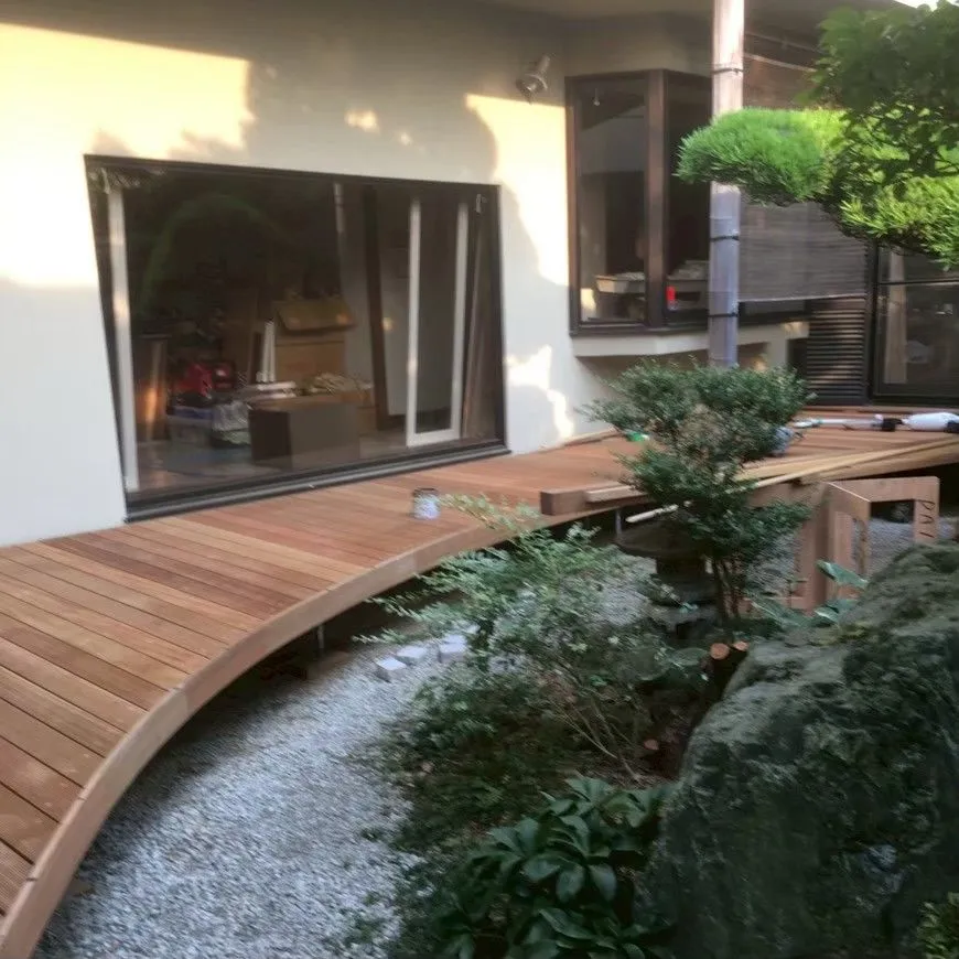 住宅の庭と建物に沿って続く曲線の木製デッキの広い全景